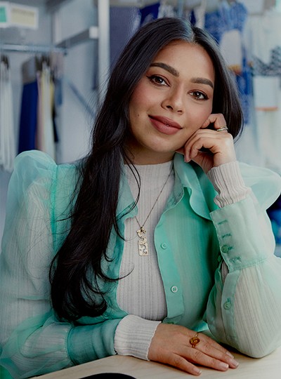 Female sat at a table leaning on her hand, looking into the camera