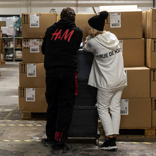 Dos colegas hablando junto a una pila de cajas de cartón