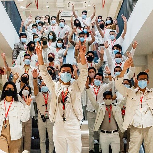 Un grand groupe d'employés du magasin portant des masques faisant signe à la caméra.