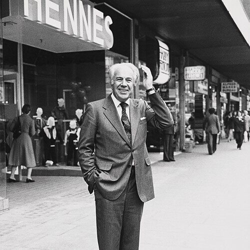 Una foto in bianco e nero di un uomo in piedi davanti a un negozio