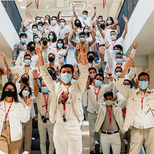 Un grande gruppo di dipendenti del negozio che indossano maschere che salutano la telecamera