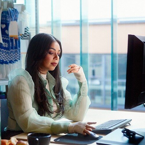 Sieviete sēž pie datora un raksta