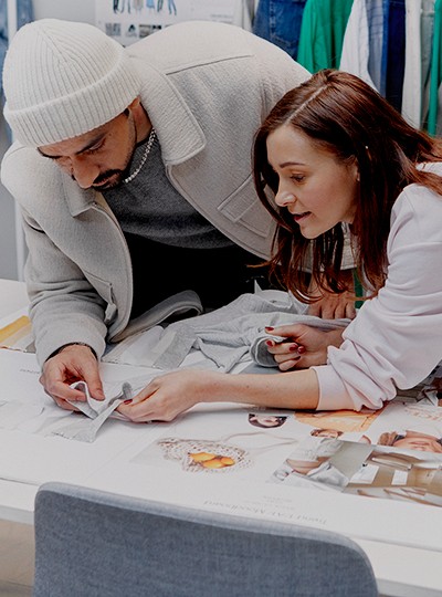 A male and female colleague leading over a table looking a fabric samples