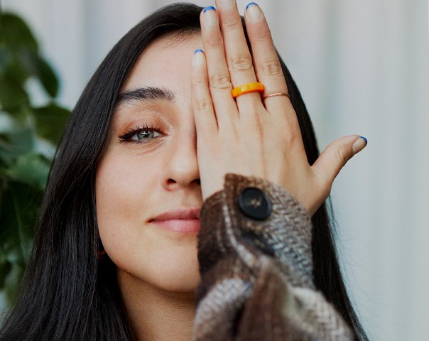 A woman looking at the camera covering one eye with her hand